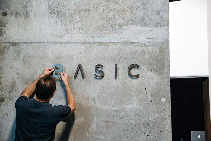  Man putting the name of the comapny Basic on the company's wall.