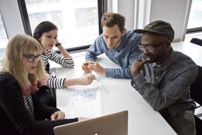  Students sitting in a group looking at a computer screen.