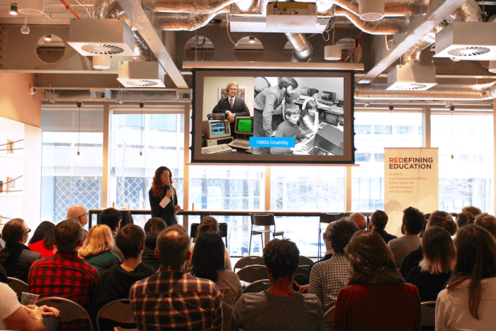  Lisa giving a talk at a conference to a crowd of people. 