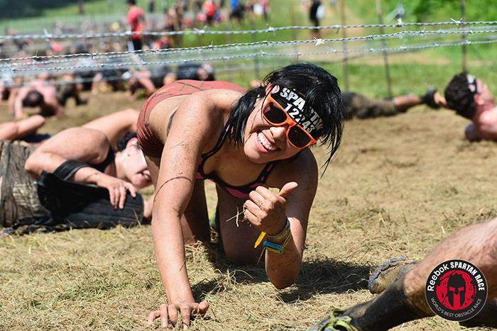 Grace Phang poses for the camera while navigating a crawling obstacle at the Reebok Spartan Race.