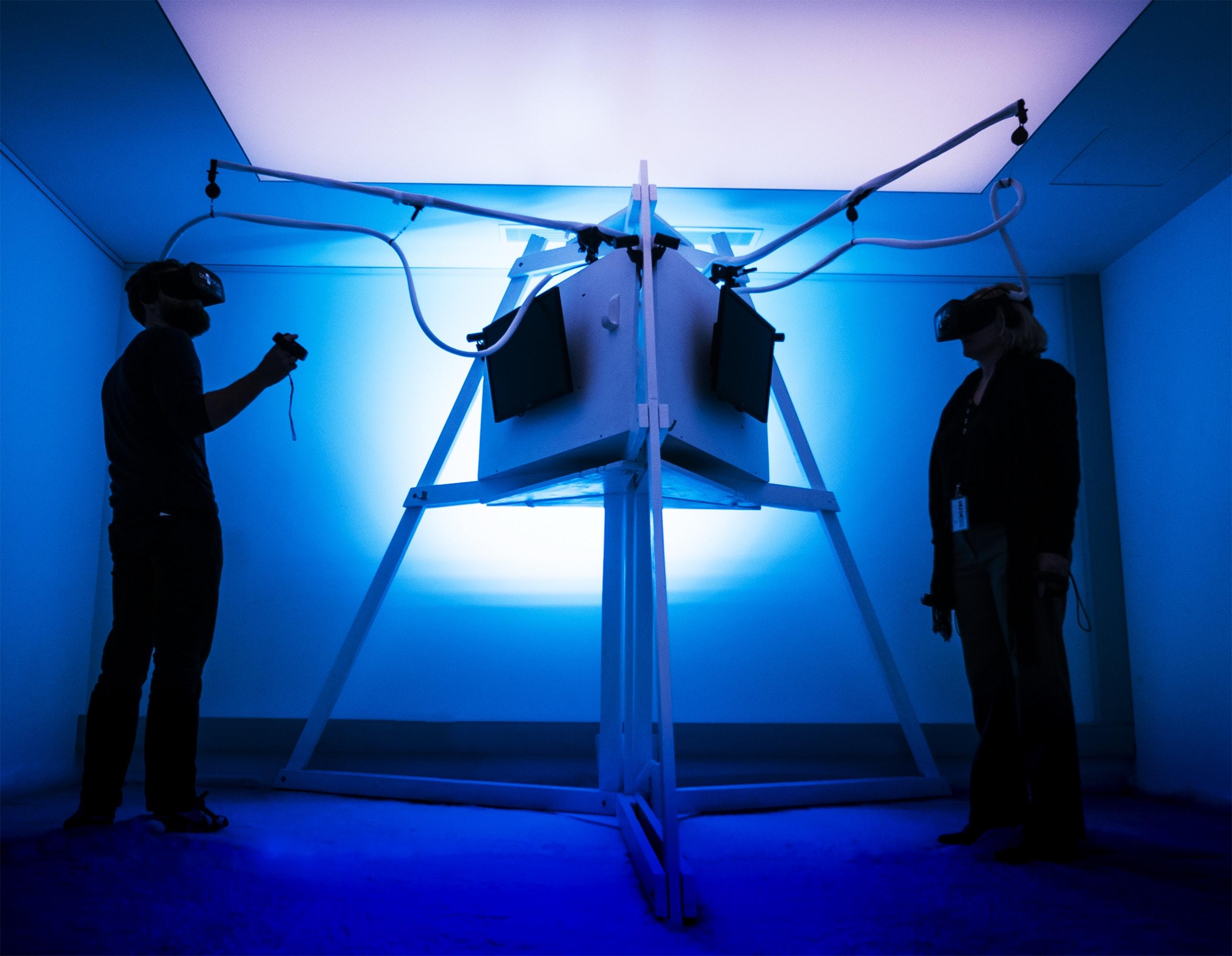 Two people in a lab setting using virtual reality equipment. 