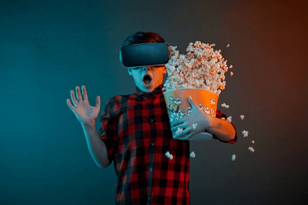 Boy getting scared and dropping popcorn while watching a movie using virtual reality