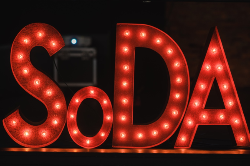 Neon sign in red lights that spells out the acronym SODA