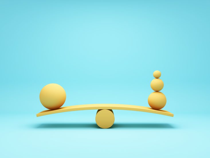 Image of a large 3D ball on one side of the scale in balance with three smaller balls on the opposite side. 