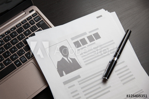 Image of an open laptop with paper and a pen on top of the keyboard.