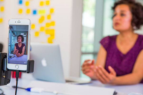 Image of a smart phone recording a woman being interviewed.