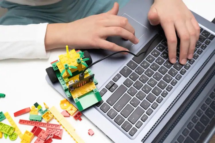 Person using a laptop with a motorized lego set.