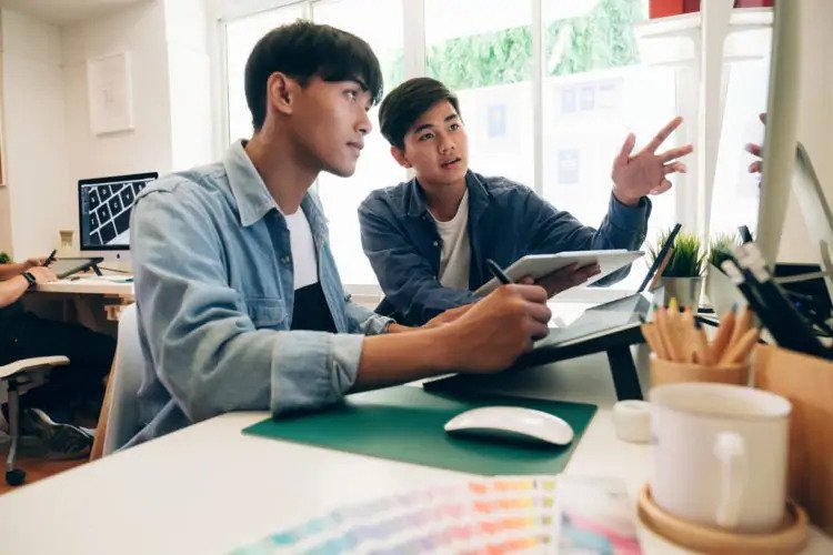 UX designers collaborating looking at a monitor and taking notes.