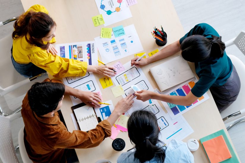 Team members sitting around a table creating a paper prototype together.