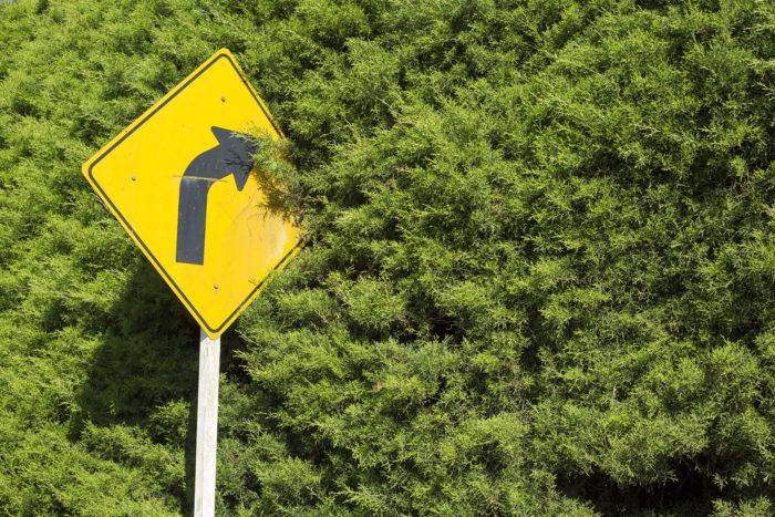  Yellow sign on the side of the road with an arrow indicating the road curves ahead.